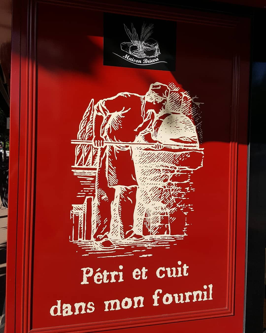Red bakery sign of a baker with wheat