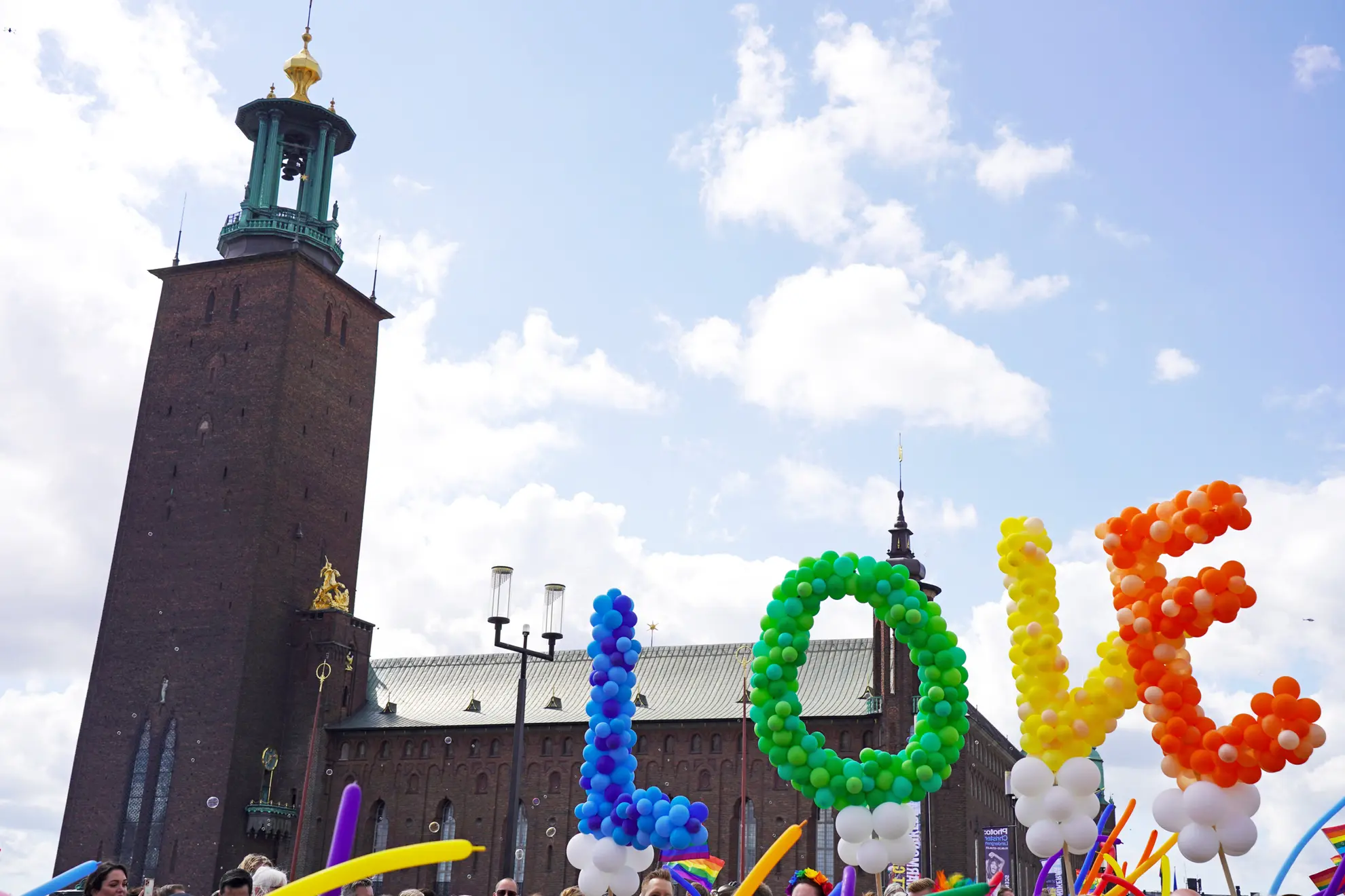 A LGBTQ+ love parade in Sweden with letters love in coloured balloons over a church 